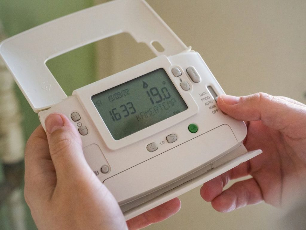 A person holding a white control device with a digital display reading 63.2