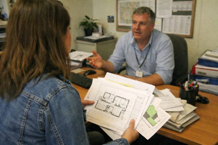 an illustrative image of a person talking to a representative at a local council about permissions