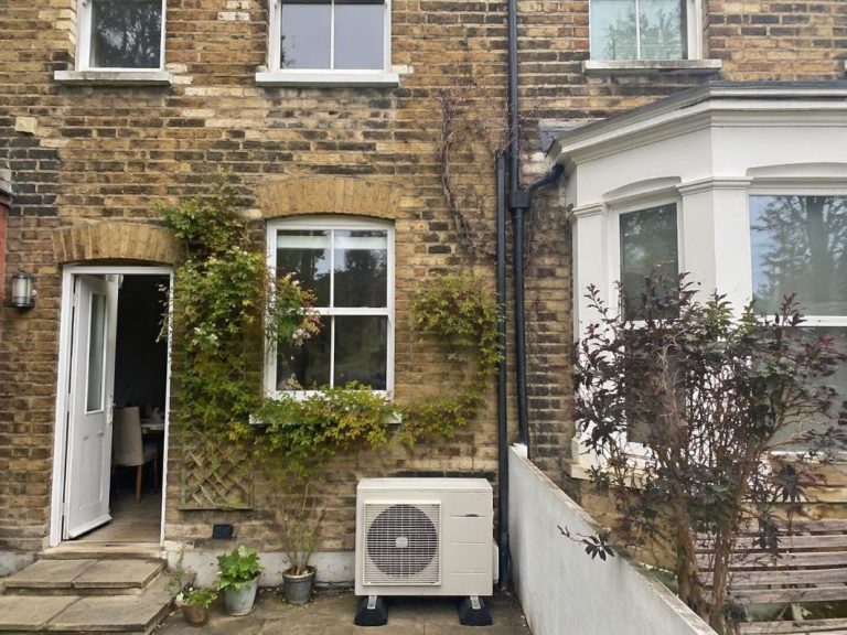 an illustrative image of an exterior London terrace house showing a discreetly installed air conditioning outdoor unit near the back wall