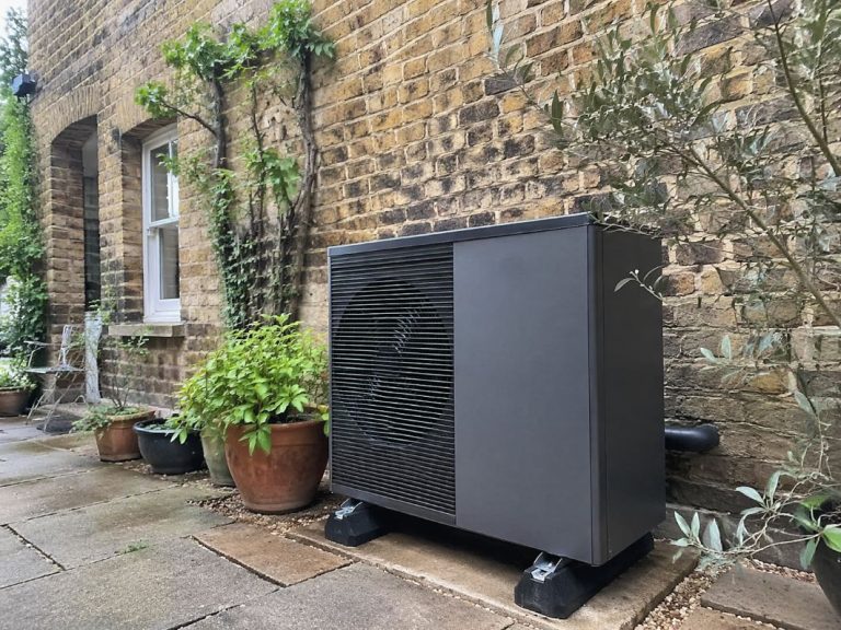 an illustrative image of an external heat pump unit installed beside a classic London brick townhouse