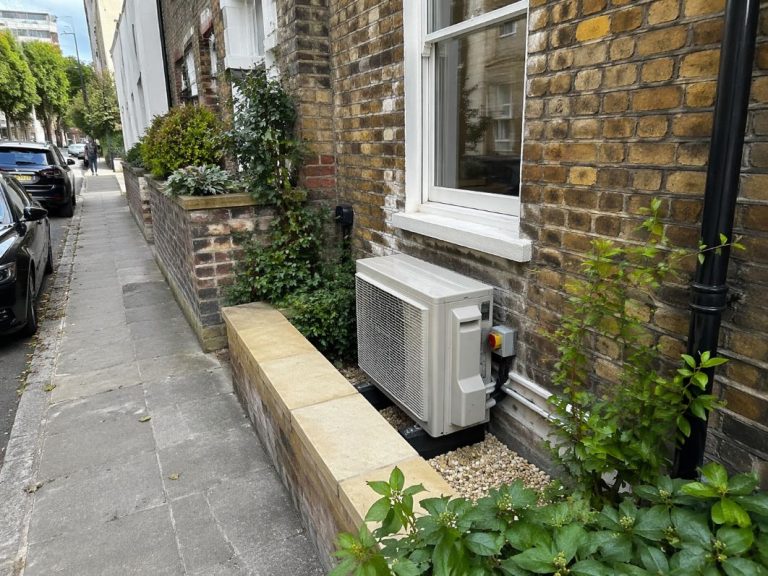 an illustrative image of n exterior rear wall of a period London house showing one discreet outdoor condenser unit installed in a constrained space